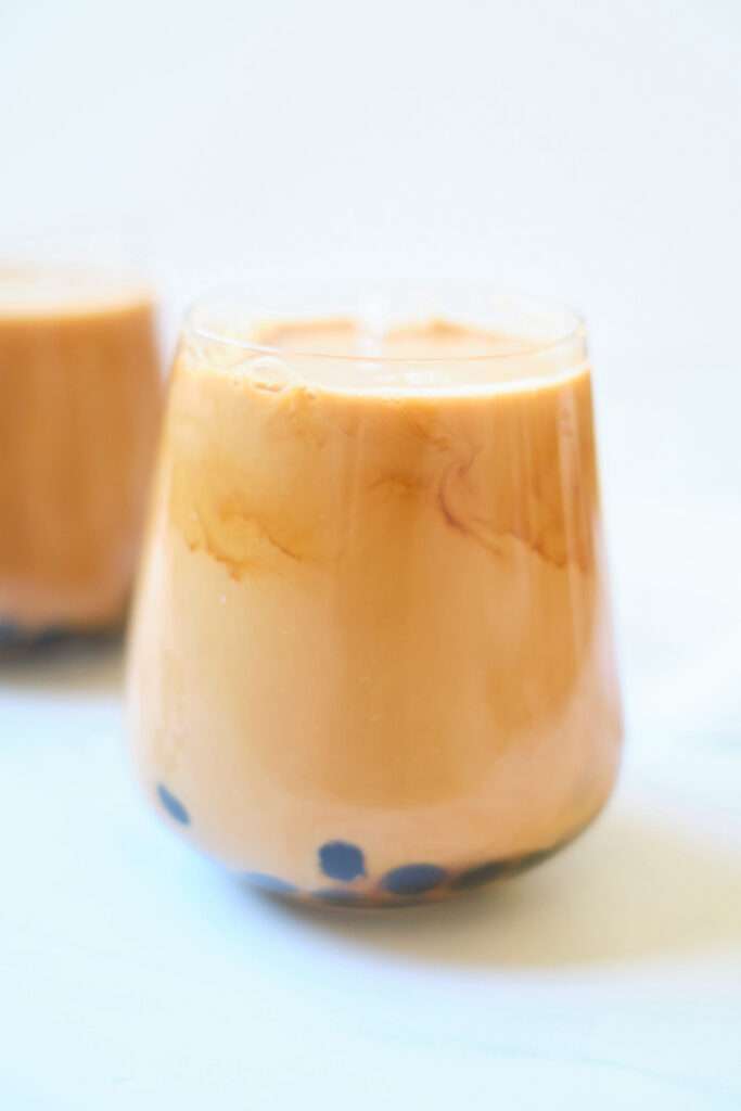 Iced Thai milk tea with boba pearls in a clear glass