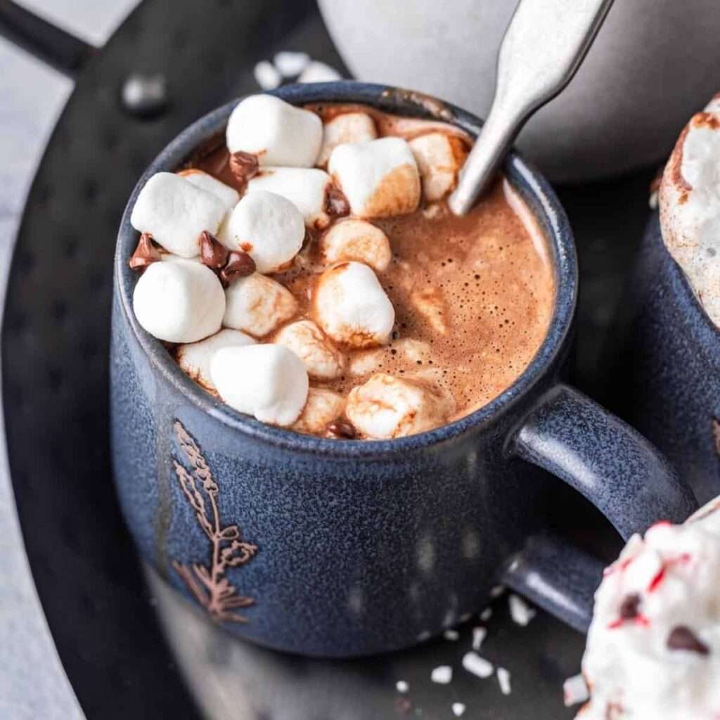 Hot cocoa with mini marshmallows in a blue ceramic mug, cozy winter drink