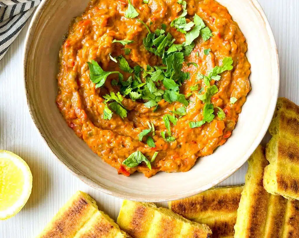 Moroccan Zaalouk Dip (Eggplant Dip) Moroccan Zaalouk Dip in a rustic bowl with a half lemon and toasted bread triangles for dipping.