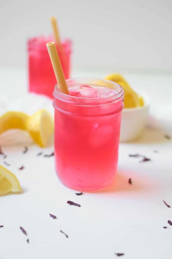 Iced hibiscus lemonade in a mason jar with straw and lemon slices