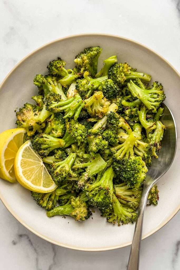 Roasted broccoli florets with lemon wedges on a plate, healthy side dish