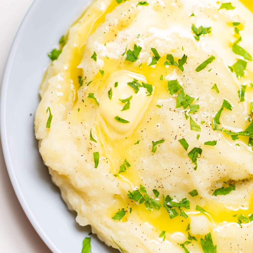 Close-up of creamy mashed potatoes with melted butter and parsley