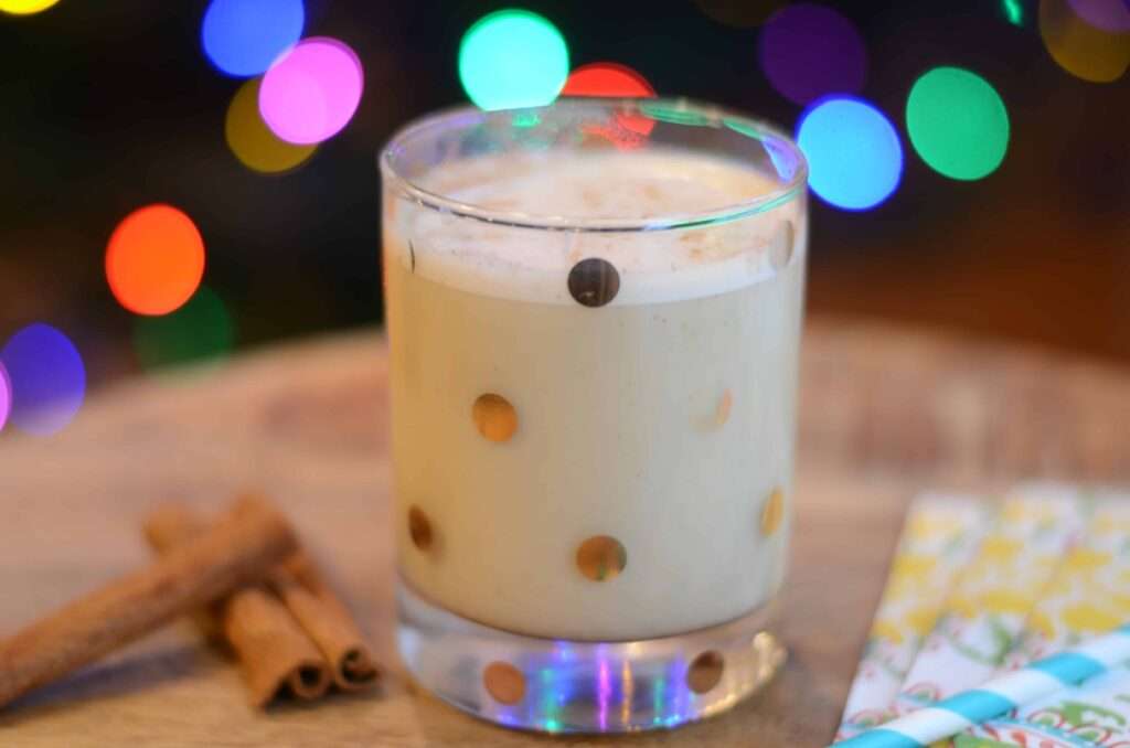 Creamy eggnog in polka dot glass with cinnamon, holiday lights bokeh