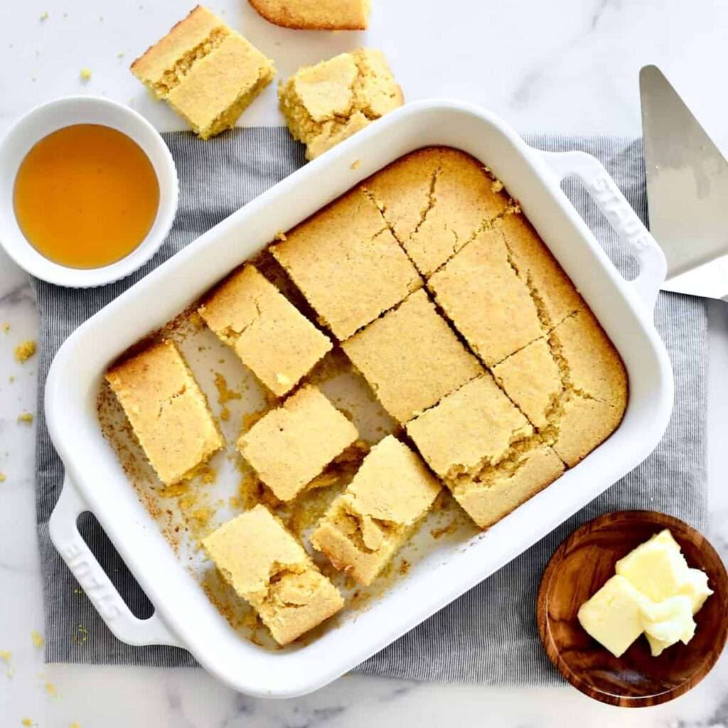 11 of the Best Side Dishes to Serve with Chili Golden cornbread squares in a baking dish with honey and butter