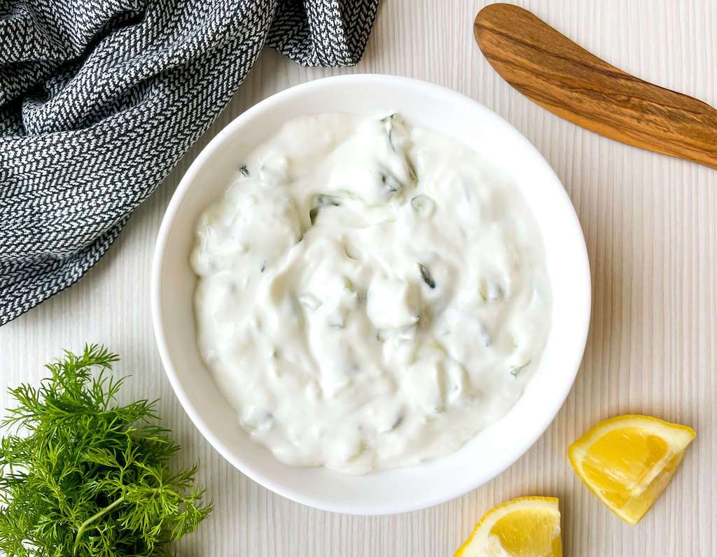 Garlic tzatziki sauce in a white bowl without toppings
