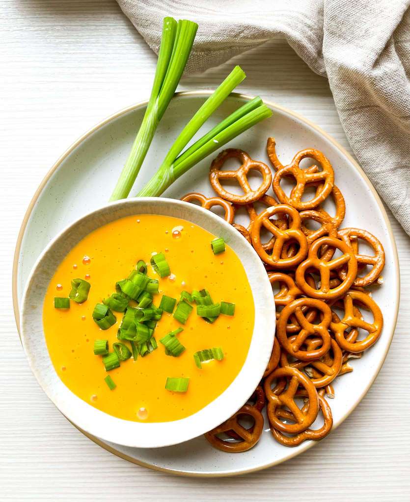 Hot Beer Cheese Dip with green onions and pretzels for dipping.