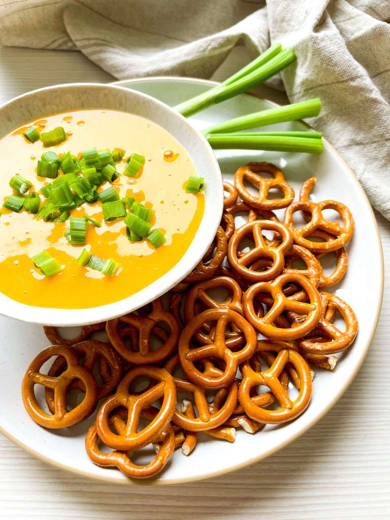 Hot Beer Cheese Dip with green onions and pretzels.