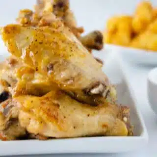 close up of lemon pepper wings with tater tots in the background