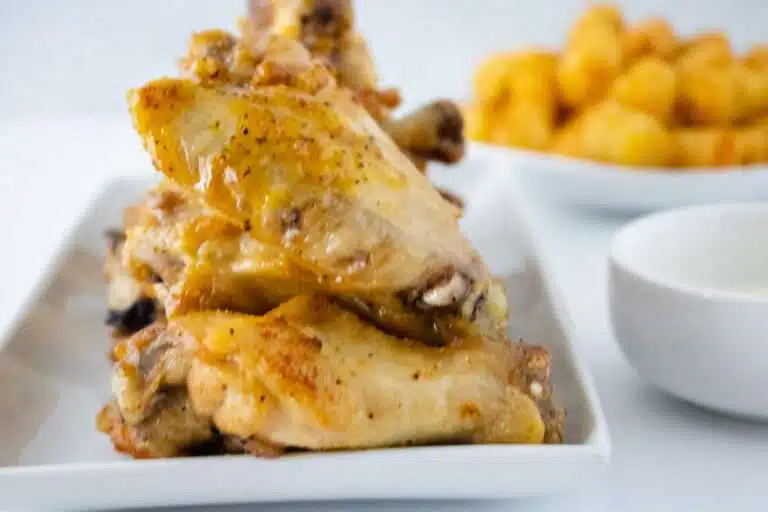 close up of lemon pepper wings with tater tots in the background
