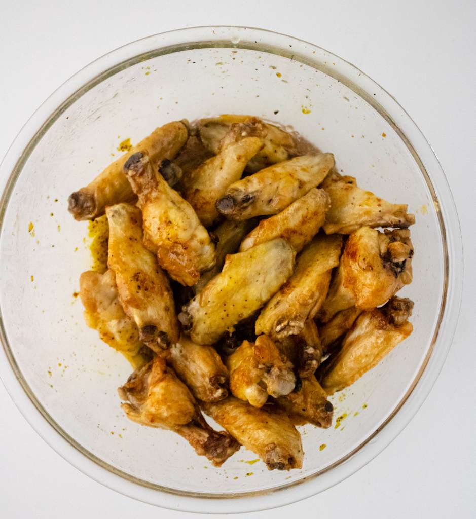 Buffalo Wild Wings Lemon Pepper wings tossed with the lemon pepper sauce in a mixing bowl.