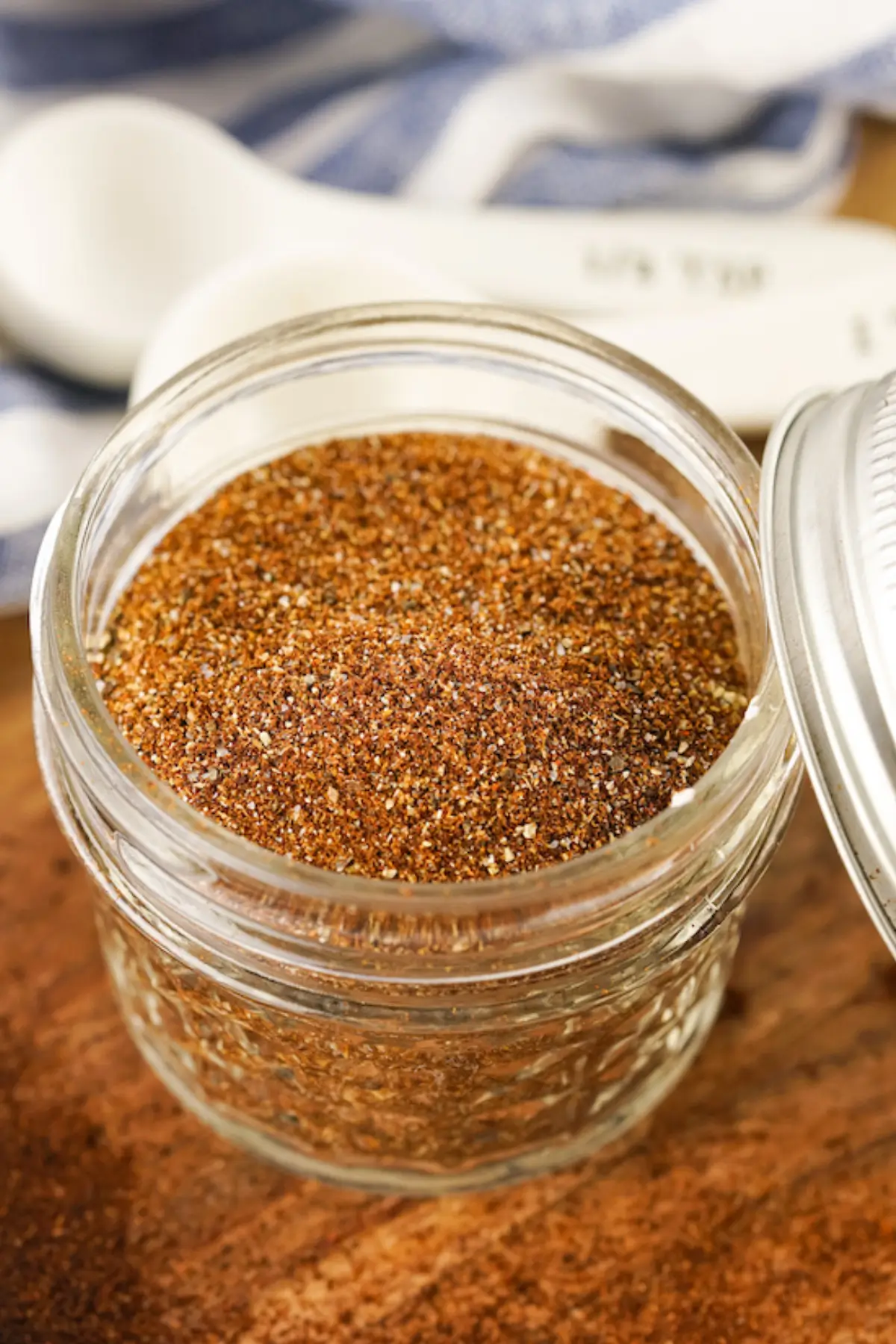 Homemade taco seasoning spice blend in a small mason jar with lid on a wooden table