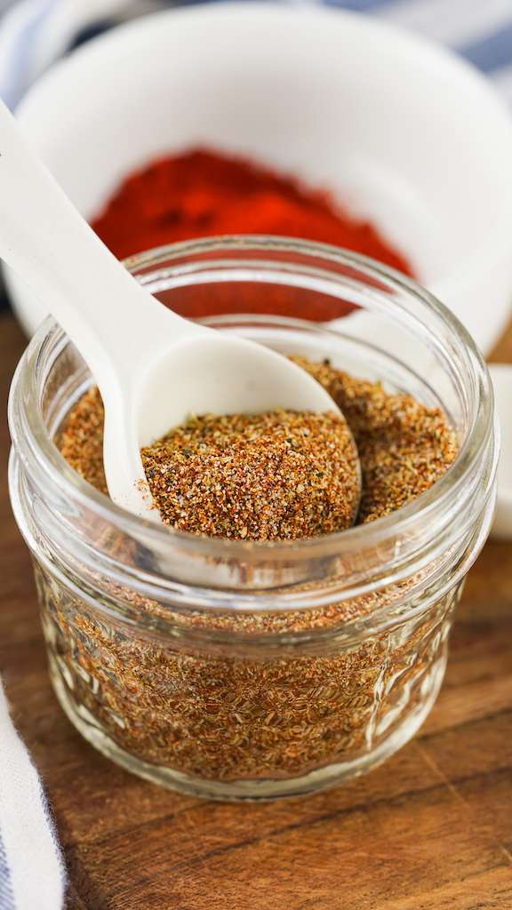 Taco seasoning, one my homemade spice blends, in a small mason jar with a white spoon.