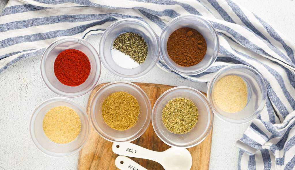 The ingredients for homemade taco seasoning in small glass bowls on a counter.