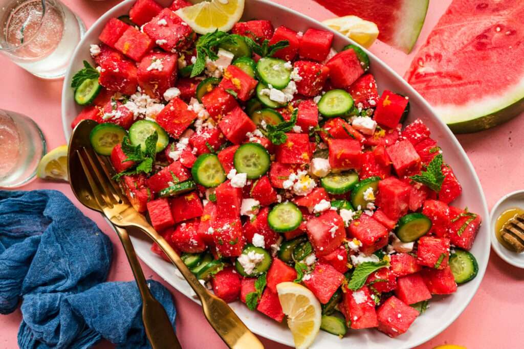 10 Fun Facts About Cucumbers Watermelon cucumber salad with feta, mint, and lemon wedges on platter