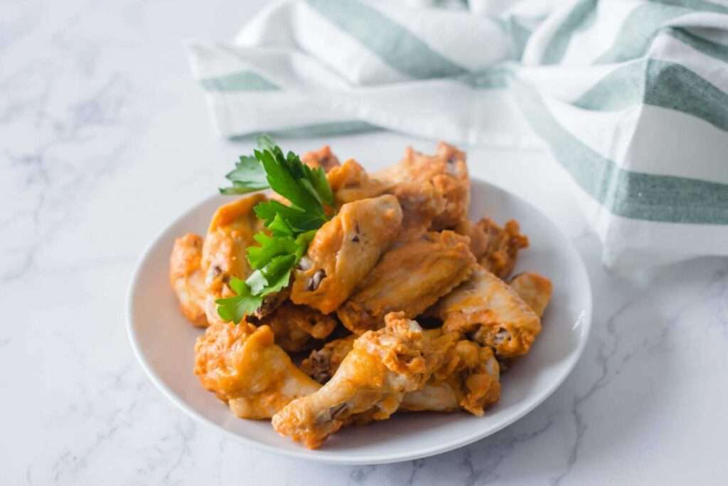7 Instant Pot Chicken Wing Recipes You'll Love Buffalo chicken wings on white plate with parsley garnish