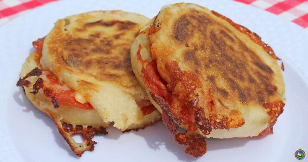 13 Pie Iron Recipes - Sweet & Savory Close-up of griddled arepa sandwiches stuffed with melted cheese and pepperoni