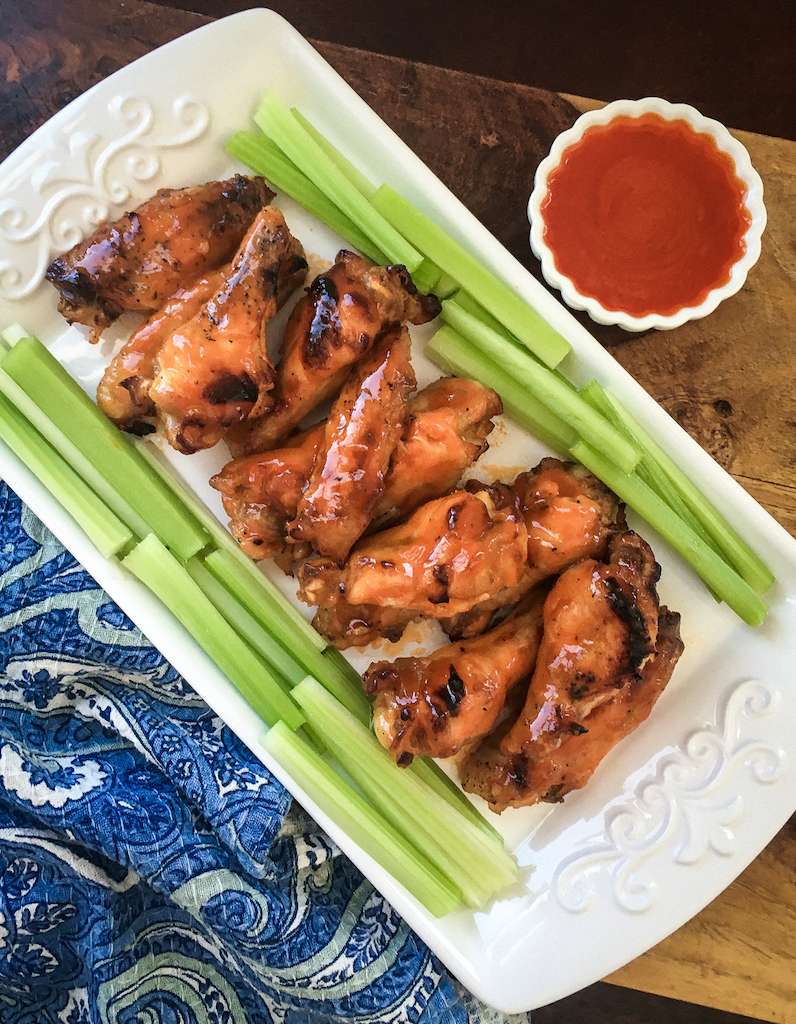 Instant Pot Buffalo Chicken Wings on a plate with celery and a side of hot sauce for dipping.