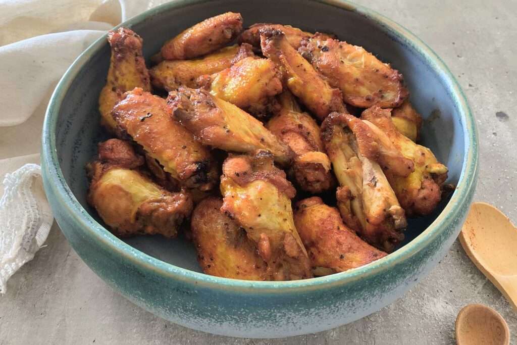 7 Instant Pot Chicken Wing Recipes You'll Love Oven-roasted chicken wings in a blue ceramic bowl, crispy and golden brown