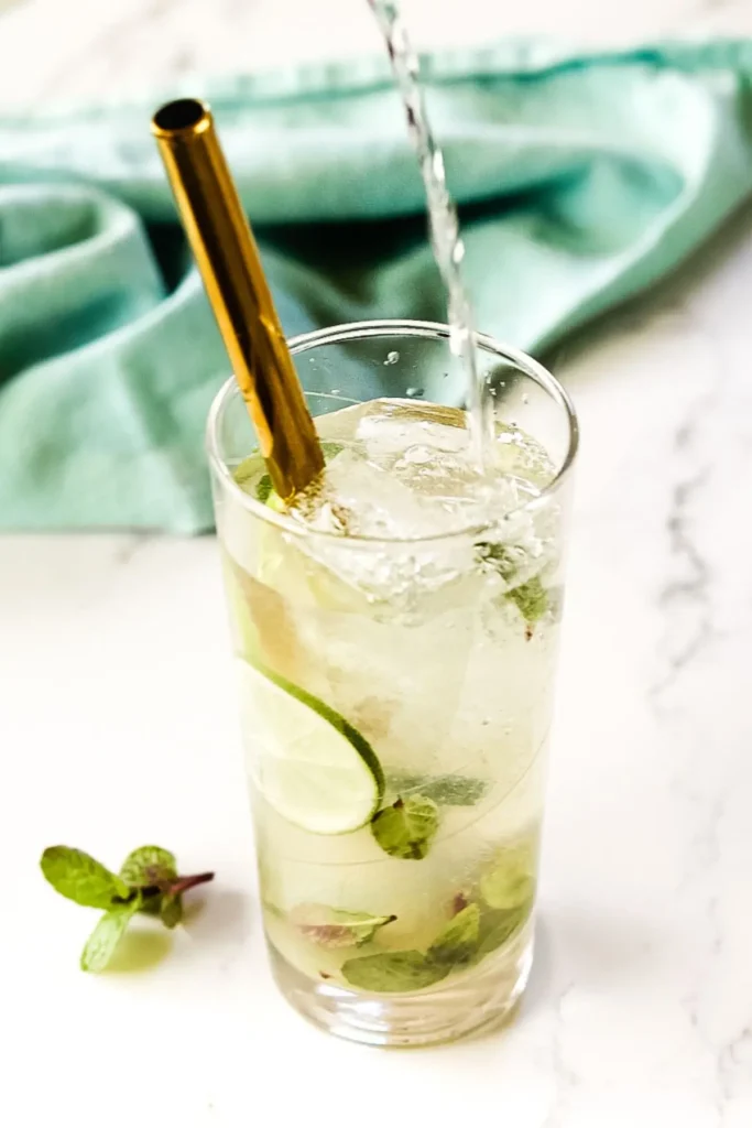 mojito with gin poured into glass with a straw