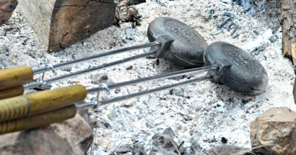 Two pie irons over a campfire ready to try these delicious pie iron recipes.