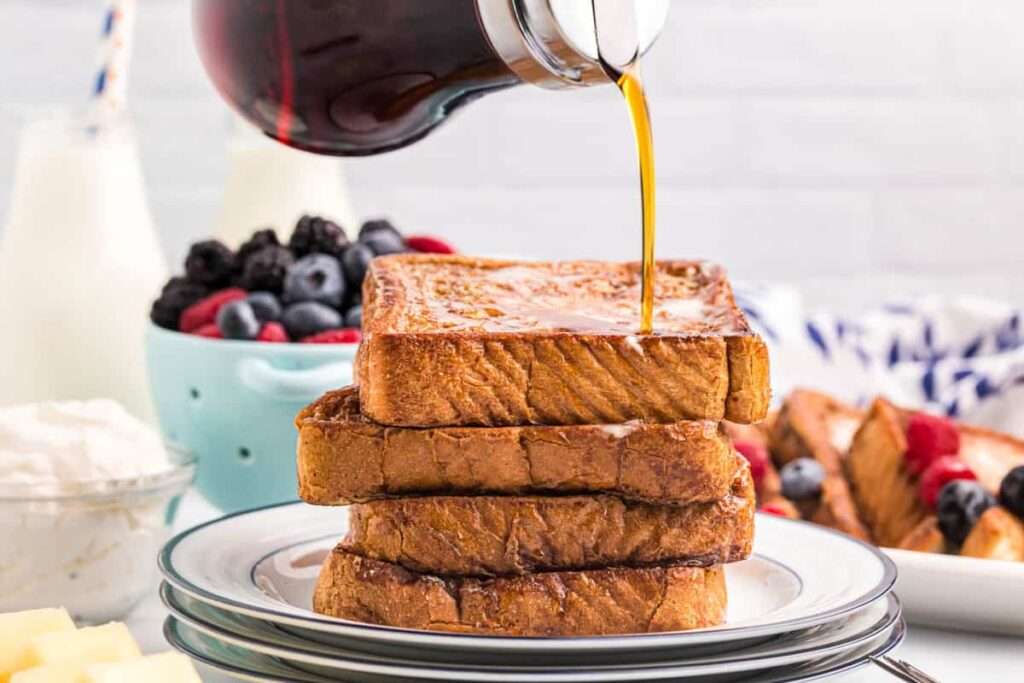 15 Best Blackstone Recipes Maple syrup poured over stacked French toast with fresh berries, breakfast scene