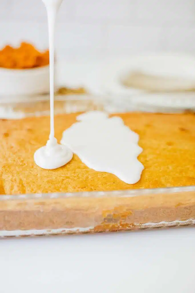 Drizzling the glaze over the cooled pumpkin honey bun cake.