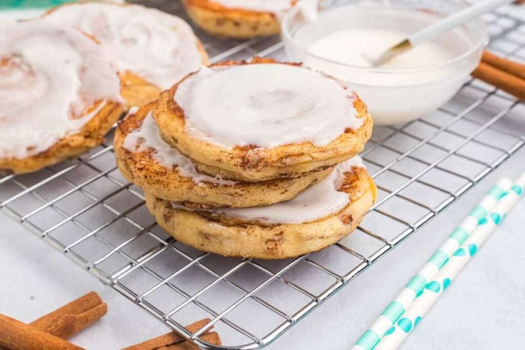 15 Best Blackstone Recipes Iced cinnamon rolls cooling on rack with vanilla glaze