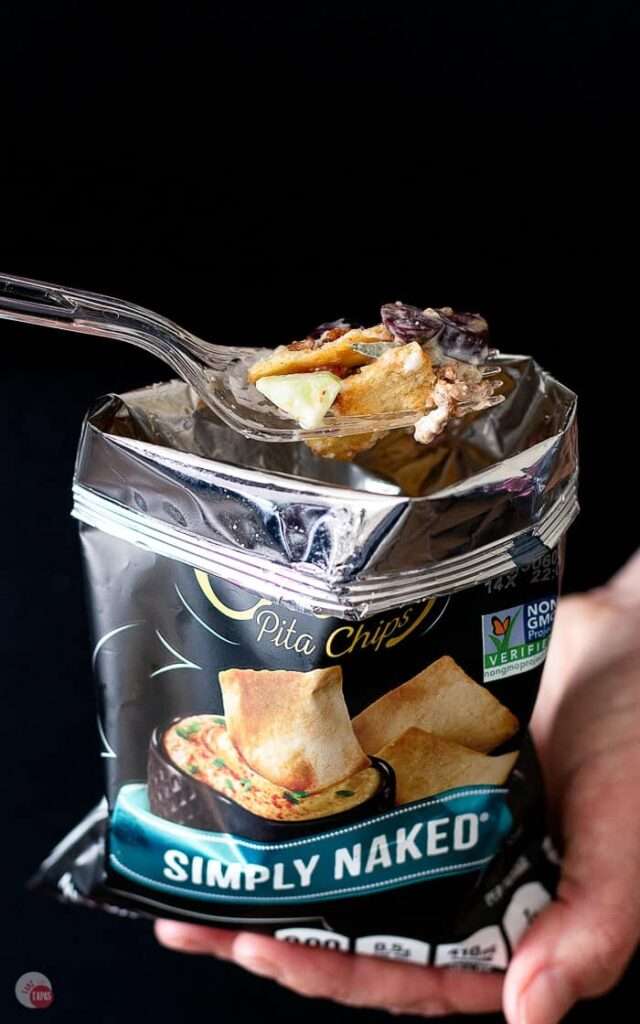 14 Walking Recipes Perfect for Camping Hand holding Stacy's Simply Naked pita chips bag with forkful snack