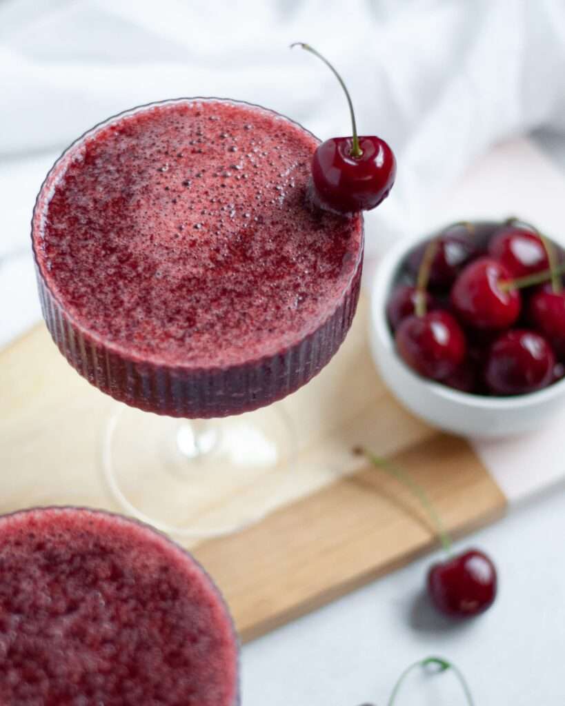 11 Refreshing Wine Slushie Recipes for Summer Cherry smoothie cocktail in coupe glass with fresh cherry garnish