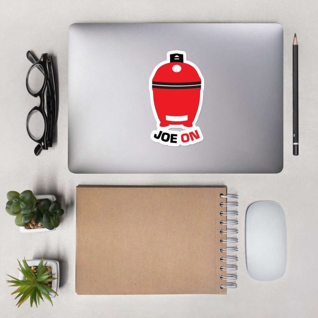 14 Unique Kamado Joe Gifts for Your Grill Master Minimalist workspace with laptop featuring red grill sticker, notebook, glasses, succulents.