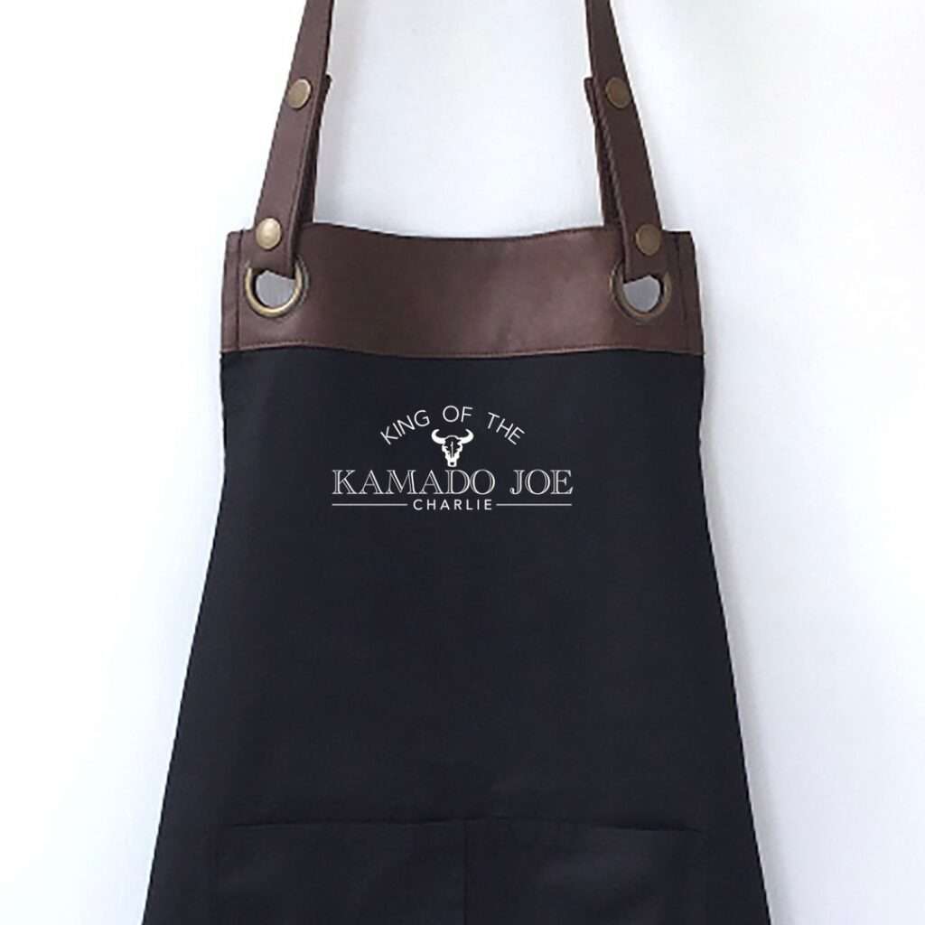 14 Unique Kamado Joe Gifts for Your Grill Master Black BBQ apron with brown leather straps and Kamado Joe logo