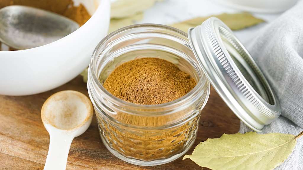 Pumpkin pie spice mix in a small mason jar with measuring spoon.