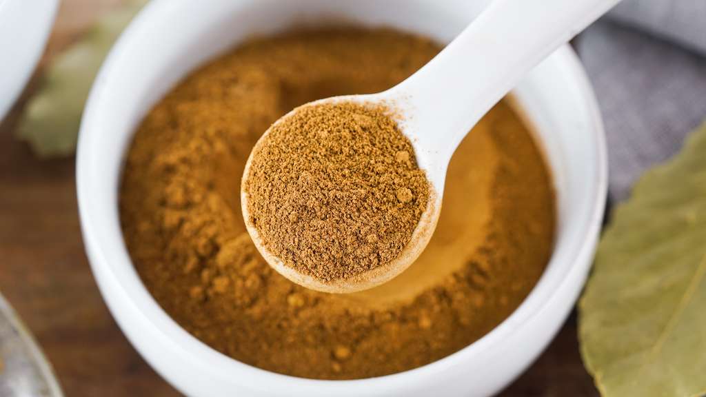 Pumpkin pie spice mix in a small white bowl with measuring spoon.