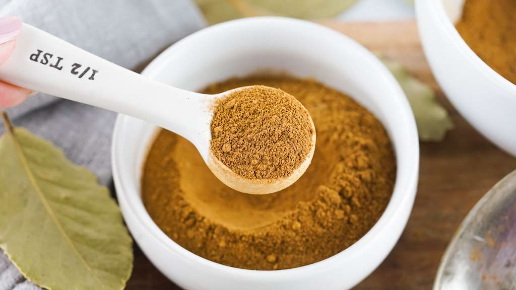 Pumpkin pie spice mix in a small white bowl with measuring spoon.