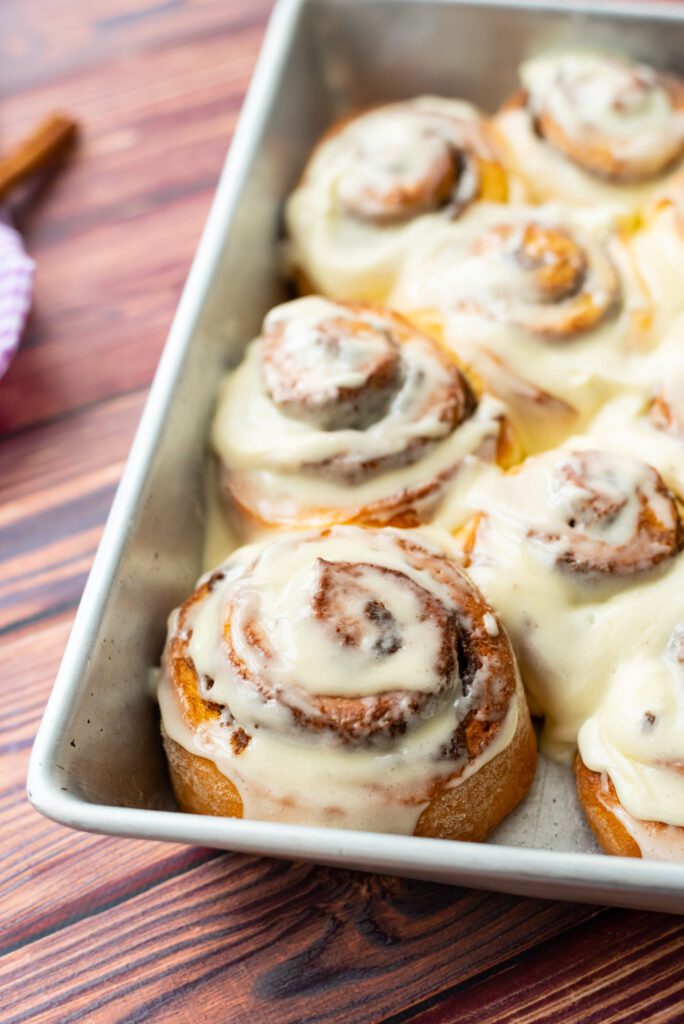 8 Traditional Christmas Flavors Freshly baked cinnamon rolls with cream cheese icing in pan