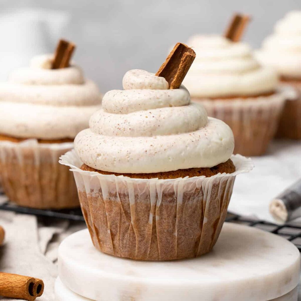 8 Traditional Christmas Flavors Cinnamon cupcake with cream cheese frosting and cinnamon stick garnish