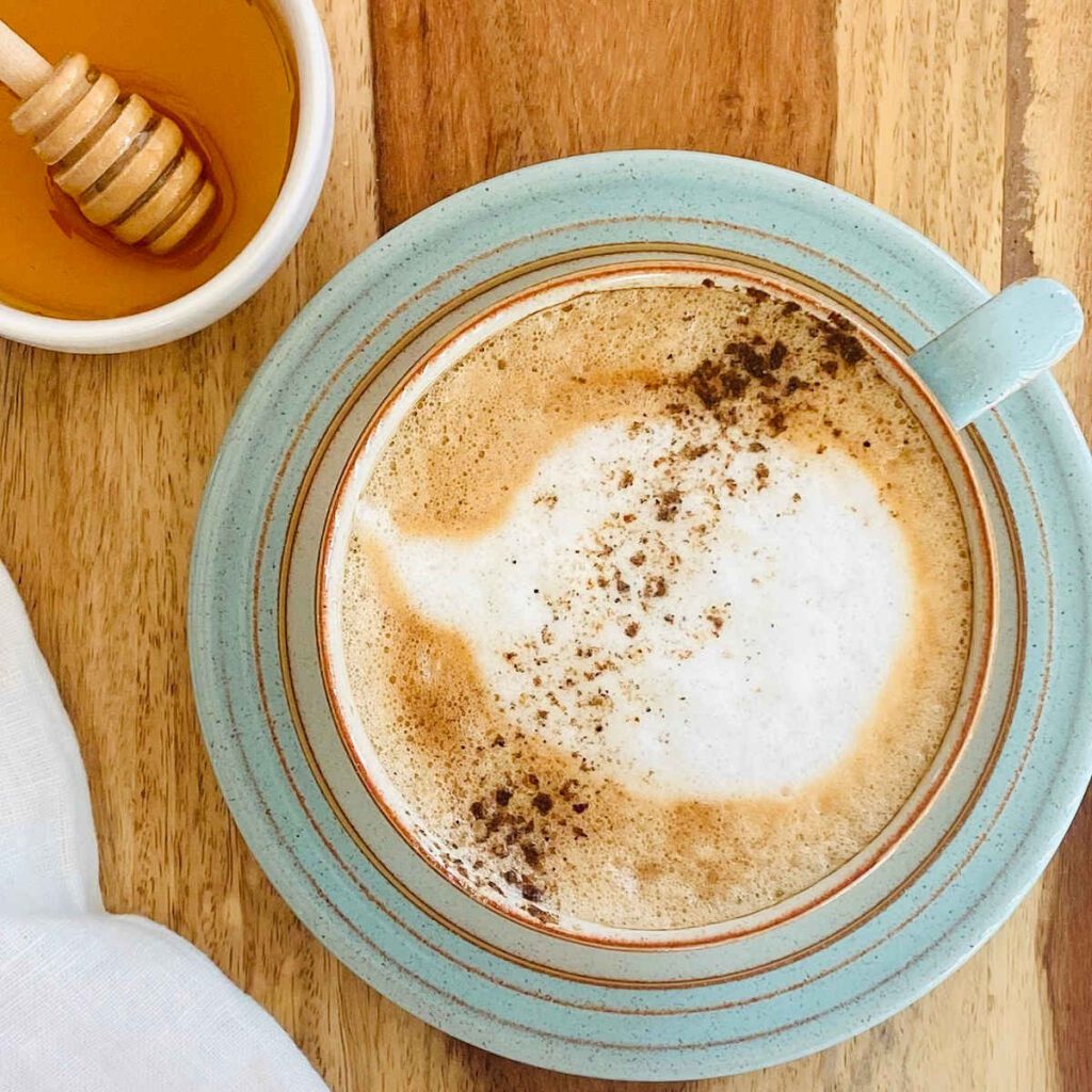8 Traditional Christmas Flavors Honey cinnamon latte in a teal cup on a wooden table