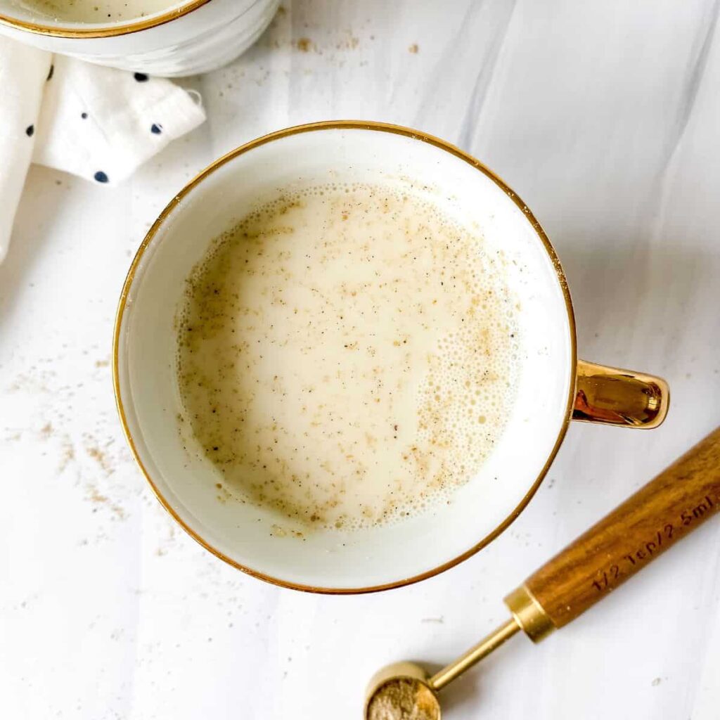 8 Traditional Christmas Flavors Creamy chai latte in a white mug with gold handle and spice spoon