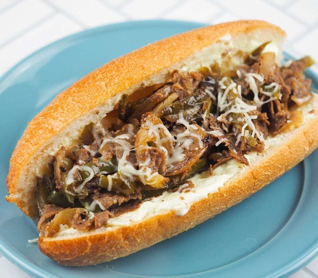 15 Best Blackstone Recipes Cheesesteak on a blue plate.