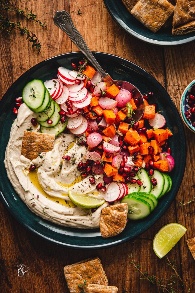 8 Traditional Christmas Flavors Mediterranean hummus bowl with cucumber, radish, roasted veggies, pomegranate, pita and lime