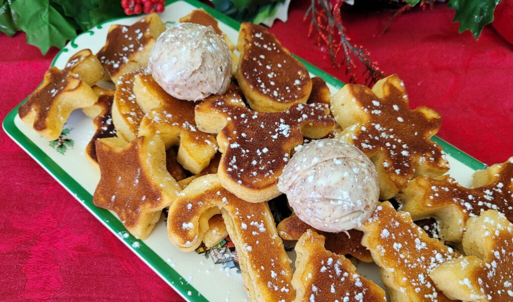 8 Traditional Christmas Flavors Christmas-shaped pancakes with powdered sugar and cinnamon butter on a platter