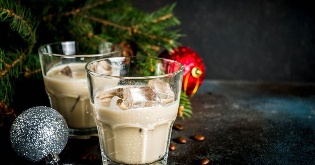 Two glasses of baileys Irish cream with Christmas decorations in the background for Christmas drinks with baileys.