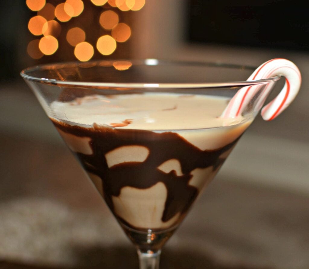 11 Christmas Cocktails with Baileys Peppermint chocolate martini with candy cane garnish and bokeh lights
