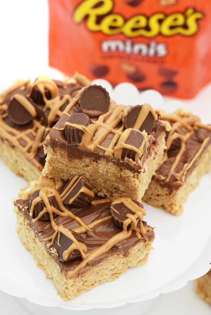 Reese peanut butter cups cereal treat bars stacked on a white plate.