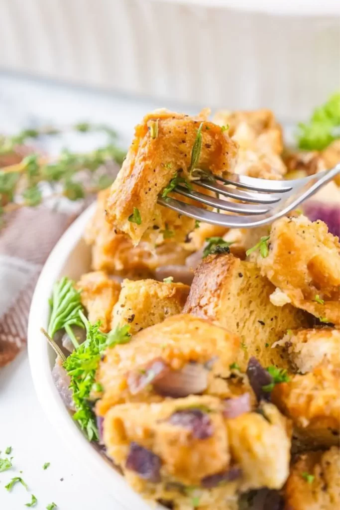 Close-up of Thanksgiving herb stuffing with crusty bread cubes, onions, and fresh parsley on a fork