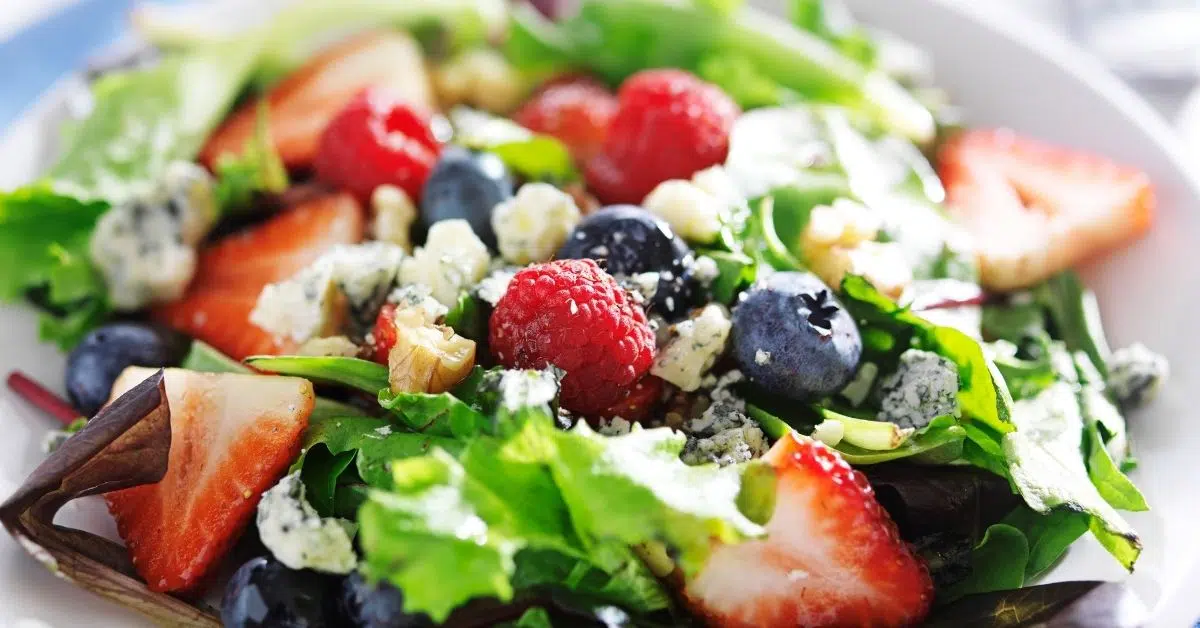 Fresh mixed greens salad with strawberries, blueberries, raspberries, blue cheese, and walnuts.