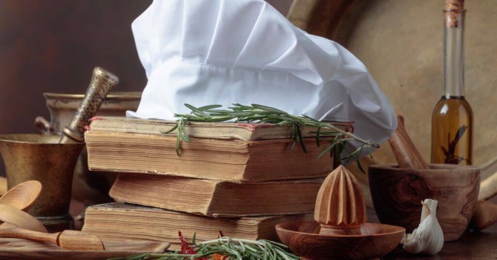 A cheff hat with pleats on a pile of books illustrating the legend behind 100 ways to cook an egg and the history of a chefs hat.