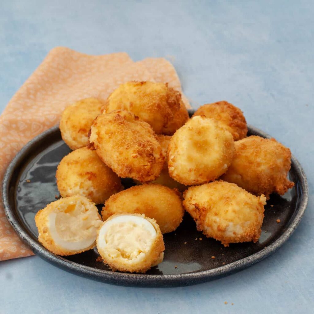 Golden fried croquettes with creamy filling on a black plate