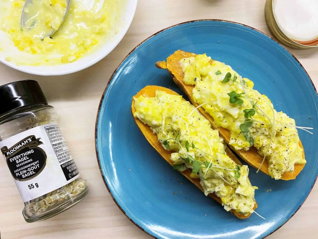 Egg salad toasts with microgreens on a blue plate, seasoning jar