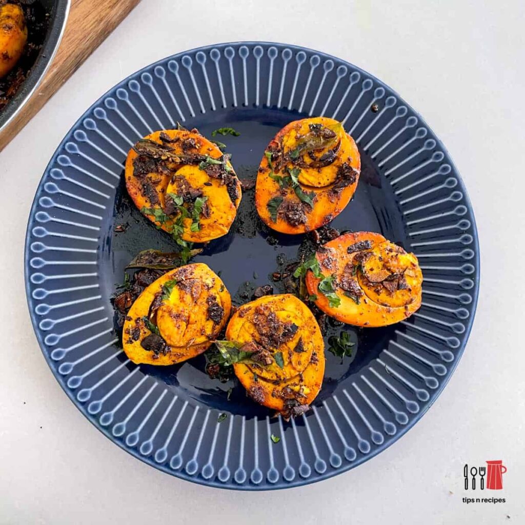 A blue plate with easy fry masala eggs on a white counter.